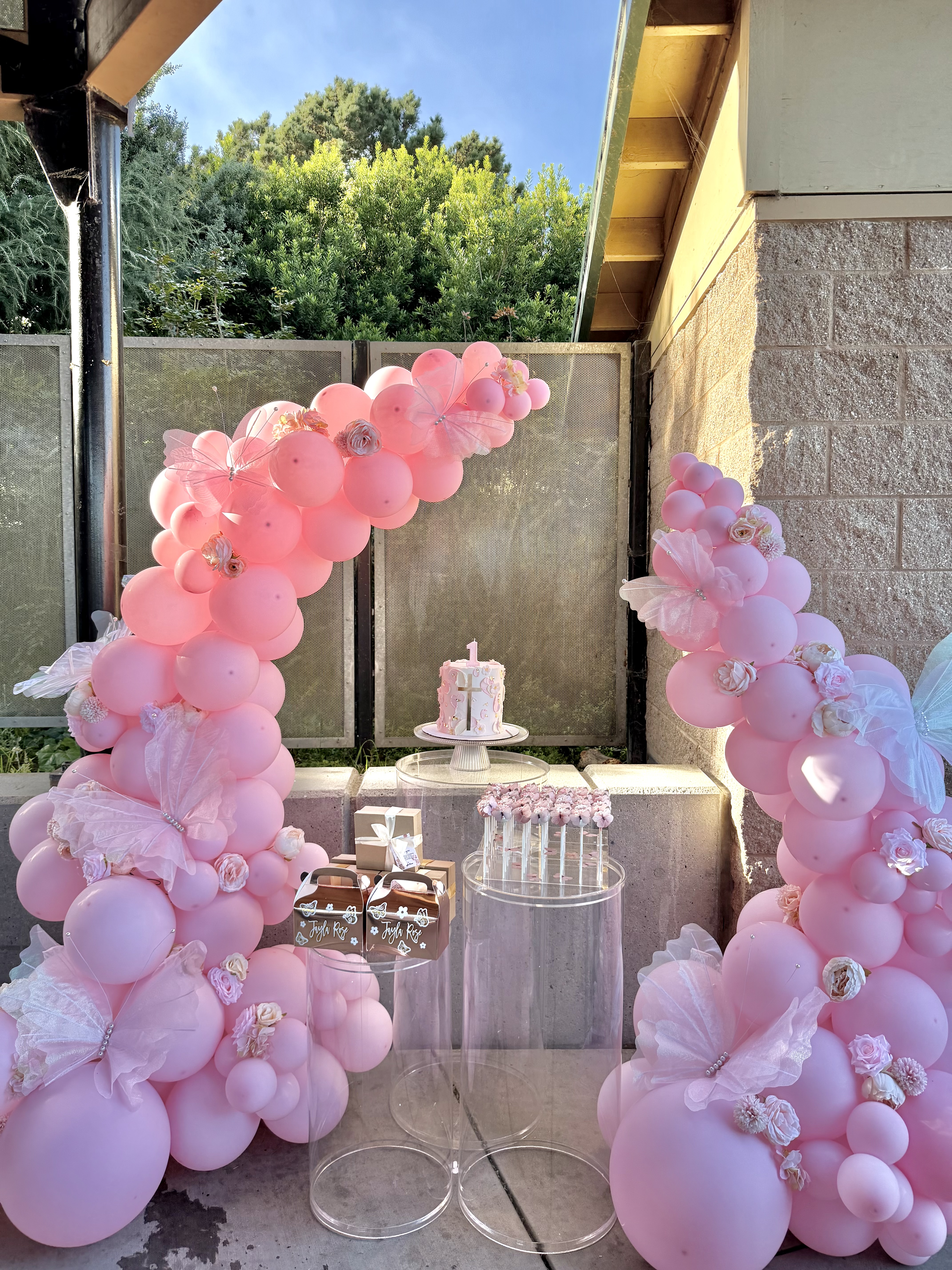 Pink balloon arch for First Communion with cross cake