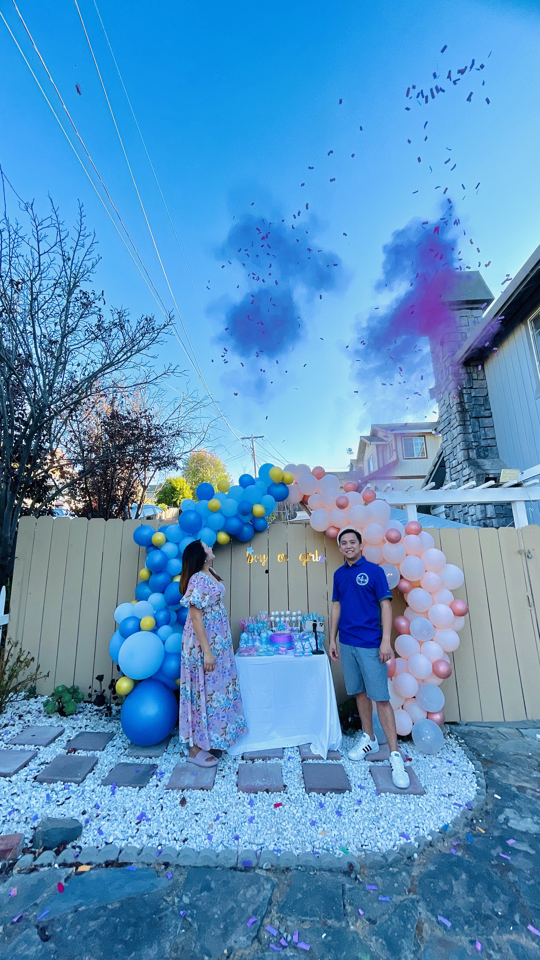 Blue and pink gender reveal balloon arch with confetti explosion