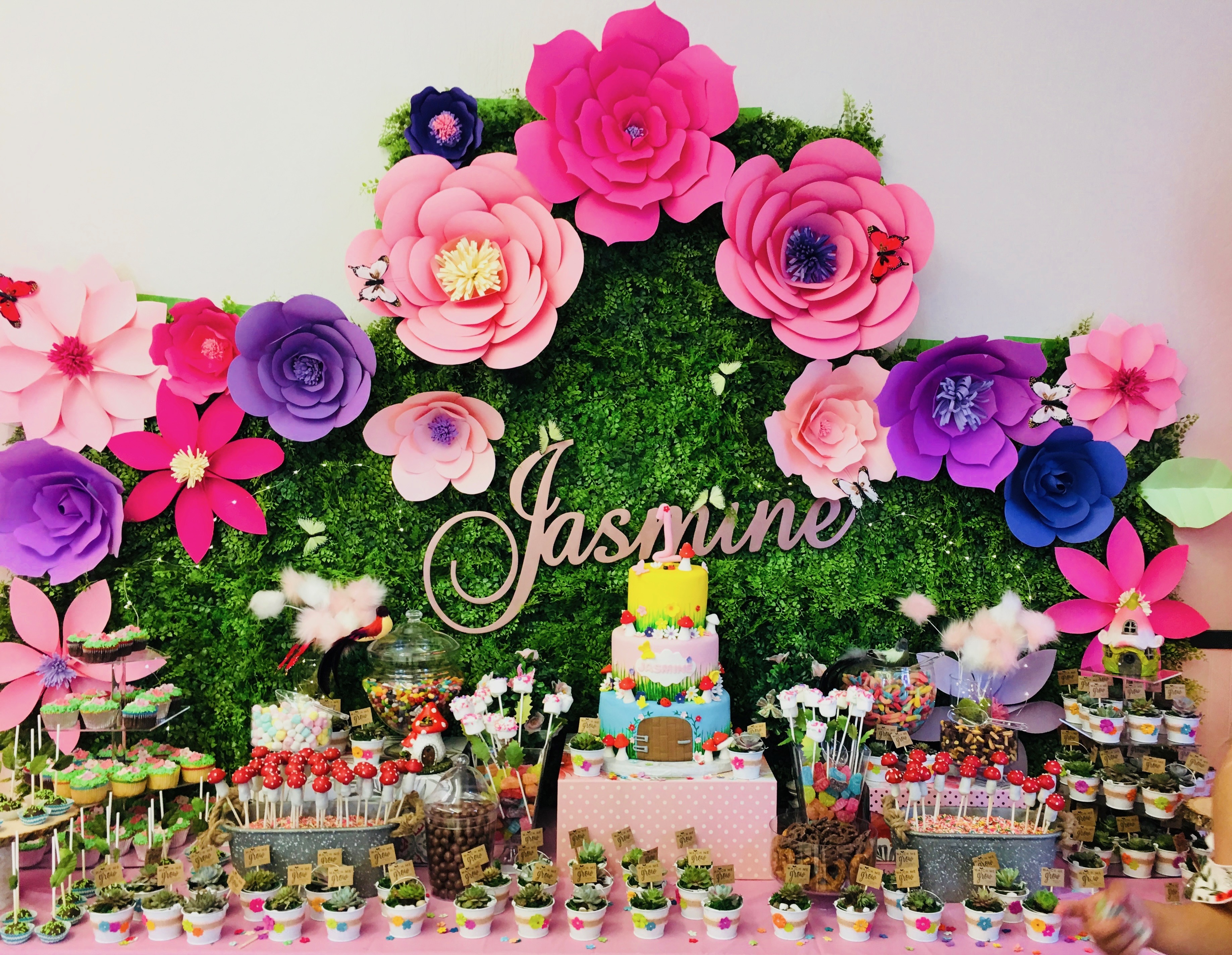 Colorful paper flower backdrop on moss wall with dessert table for Jasmine